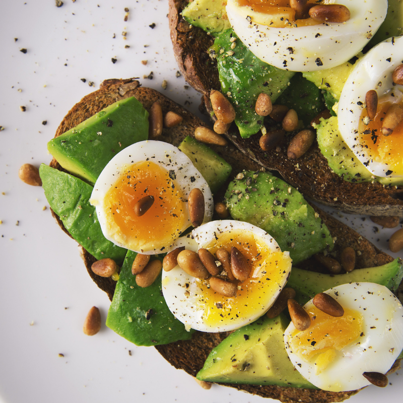 alt= Avocado toast with a hard boiled egg and pine nuts.