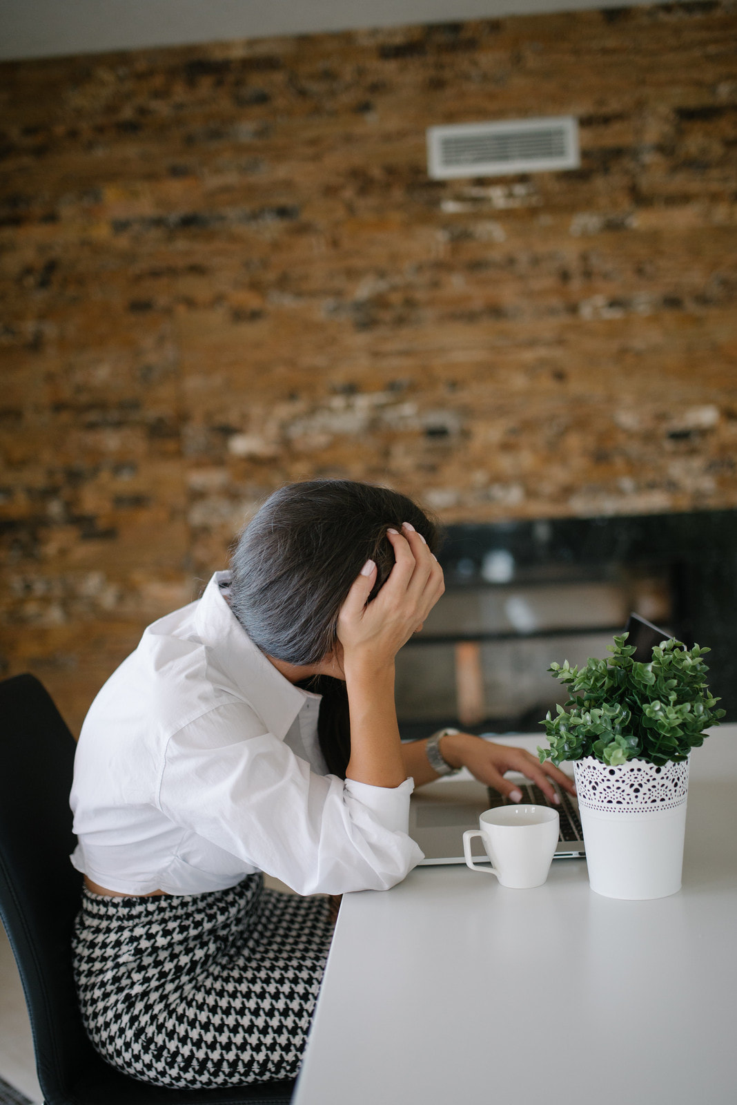 Alt= Business woman stressed with hand on head at her desk